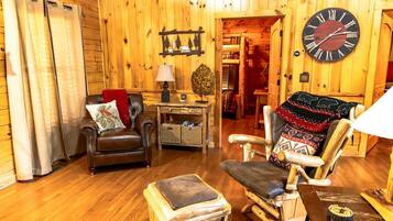 A cozy cabin interior with a wooden interior, leather furniture, and a large wall clock.