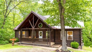 Ein rustikales Holzhaus mit Veranda, Eingangstür und einem kleinen Garten.