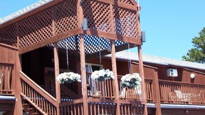 A wooden building with a balcony, two flags, and hanging flower baskets. - Sea Drift Motel (Old Orchard Beach)