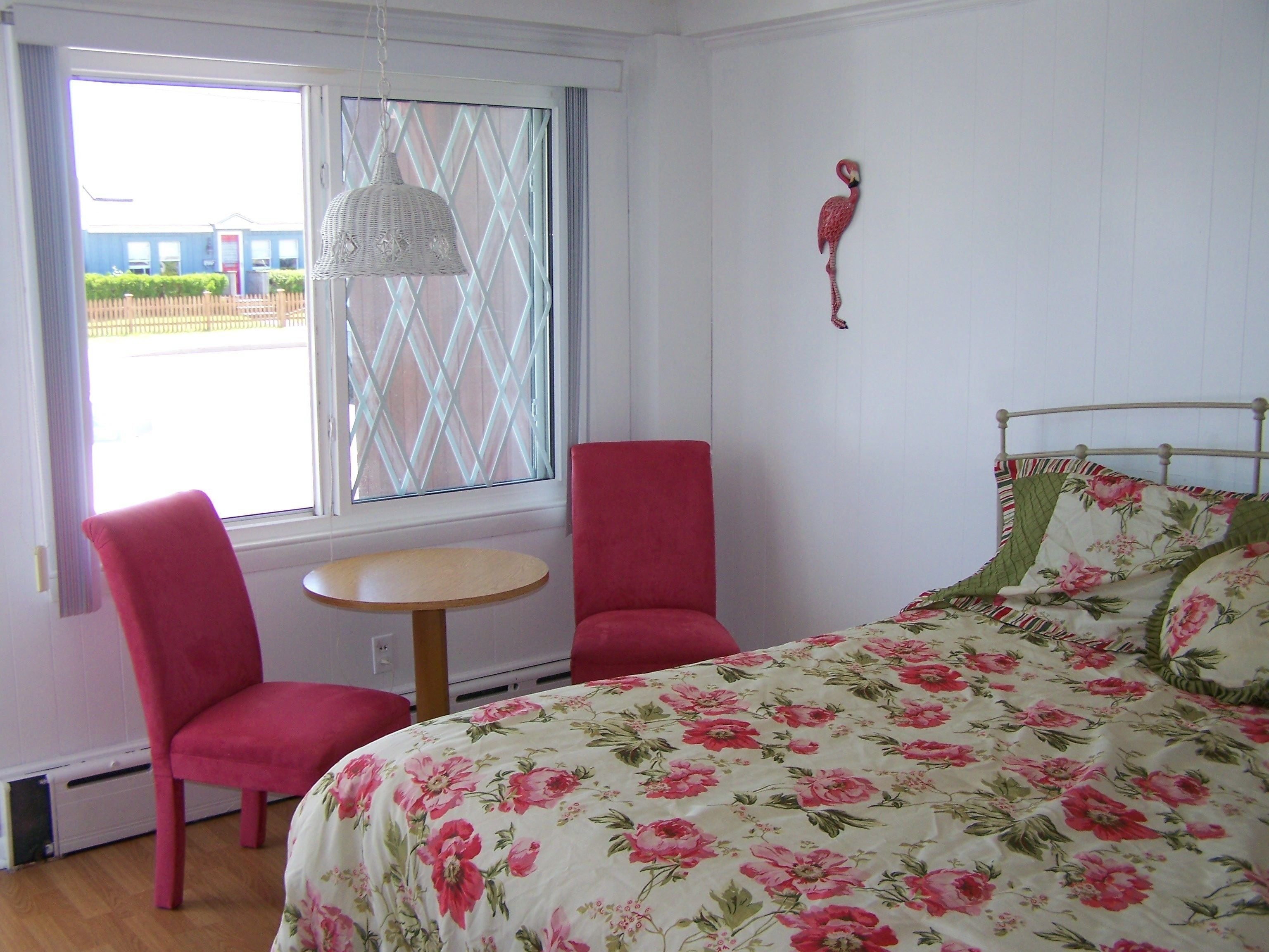 Ein Schlafzimmer mit einem Bett, zwei Stühlen, einem kleinen Tisch und einem Fenster mit Blick.