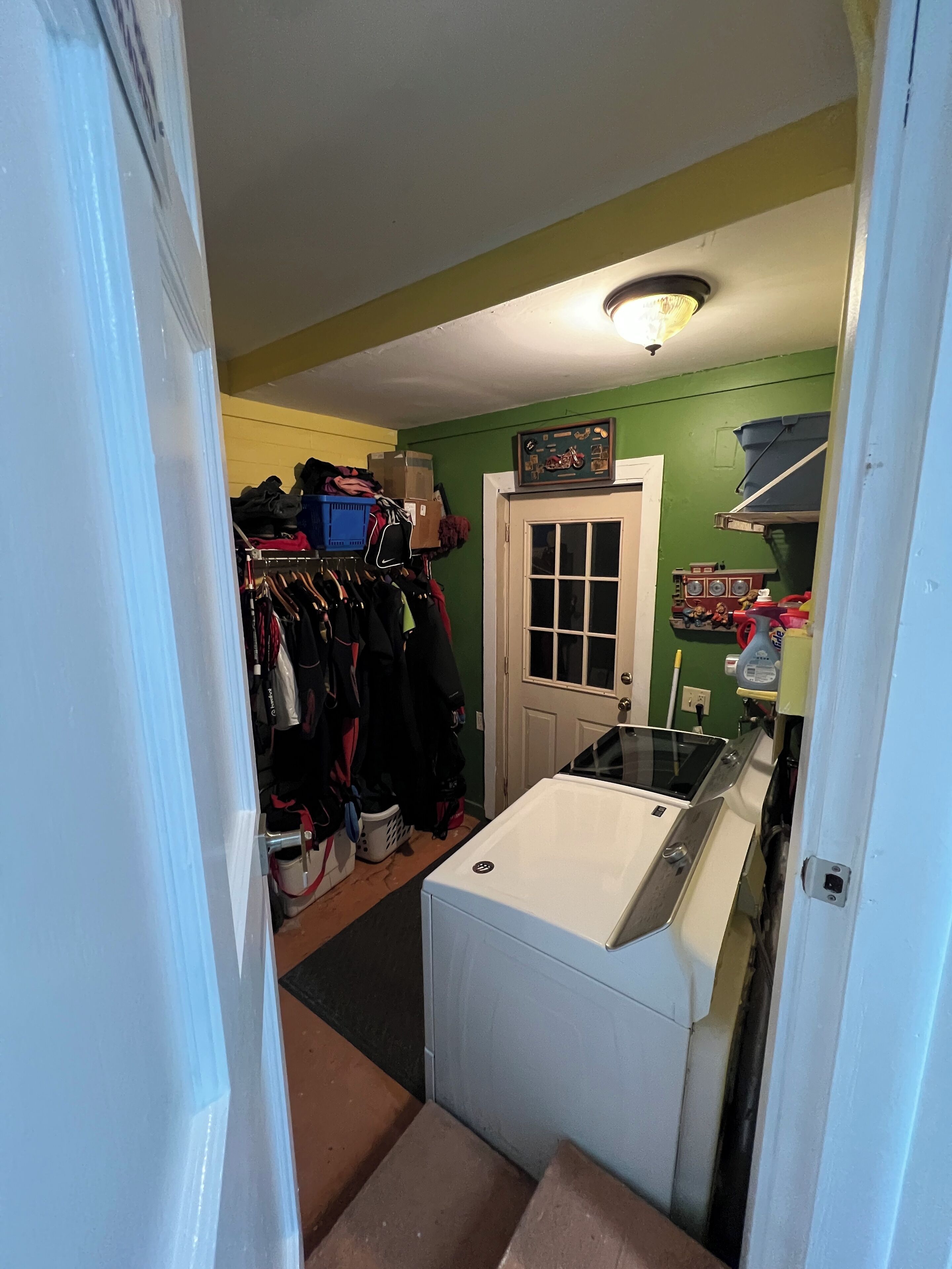 Une buanderie équipée d’un lave-linge, d’un étendoir et d’une porte donnant sur une autre pièce.