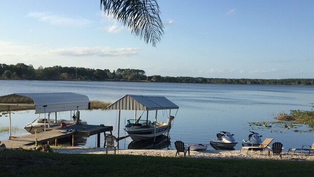 Un muelle a orillas del lago con un cobertizo para botes, una lancha pequeña y un jet ski.