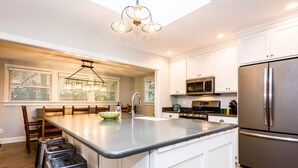 A modern kitchen with white cabinets, stainless steel appliances, and a central island with stools.