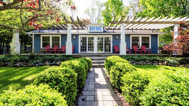 A house with a covered porch, a stone pathway, and well-maintained hedges.