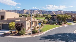 Un quartier résidentiel avec des maisons modernes, une pelouse bien entretenue et une chaîne de montagnes en arrière-plan.