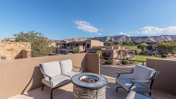 Une terrasse avec deux chaises et une table ronde, d’où l’on peut admirer un paysage montagneux.