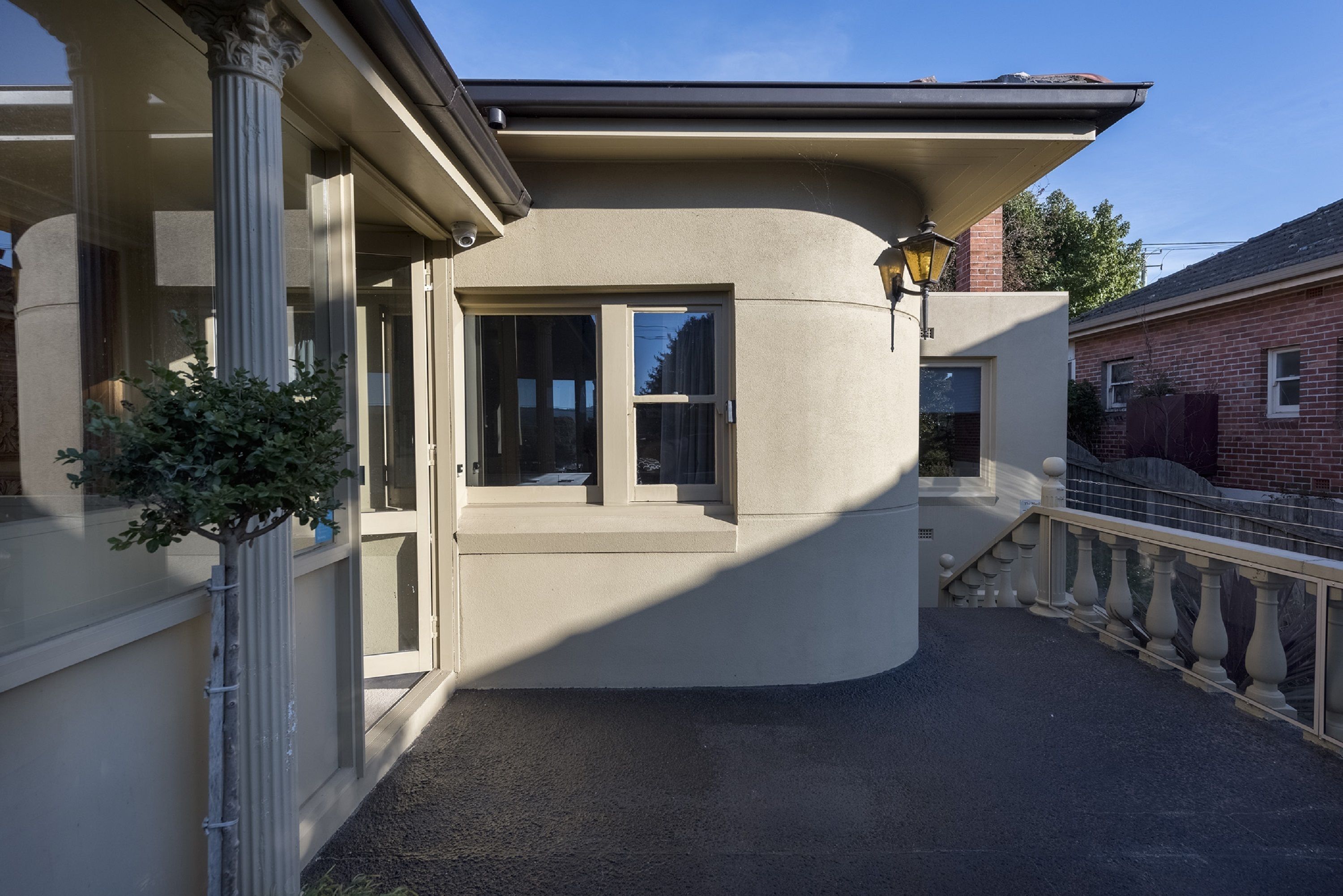 A corner building with a beige facade, a large window, and a small balcony with a railing.