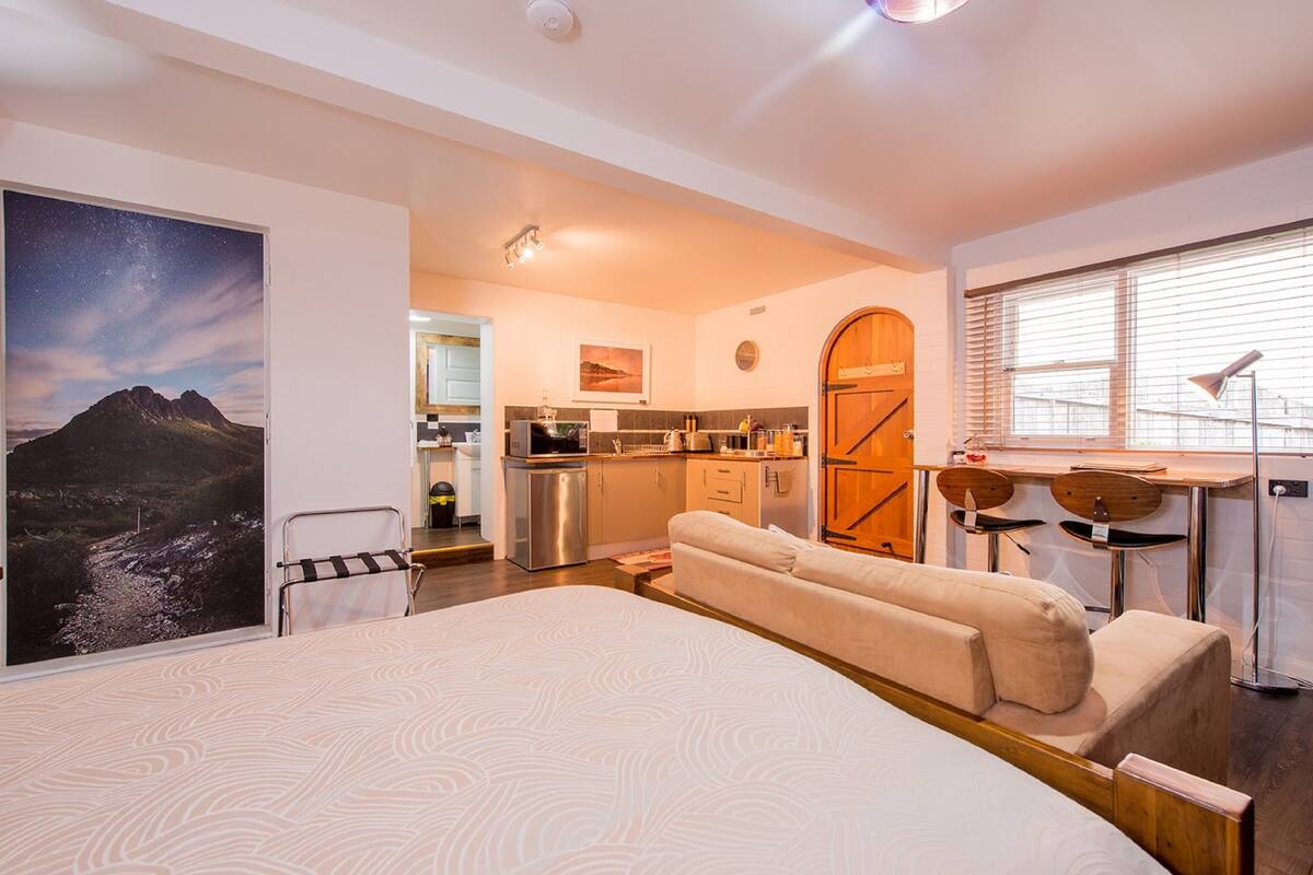 Een moderne slaapkamer met een groot bed, een kitchenette, een eethoek en een badkamer.