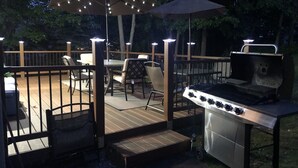 An outdoor deck with a grill, chairs, and tables under umbrellas. - Beautiful Two Story Home In long pond  pa (Long pond)