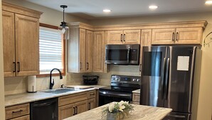 A modern kitchen with wooden cabinets, stainless steel appliances, a granite countertop, and a central island with bar stools. - Beautiful Two Story Home In long pond  pa (Long pond)