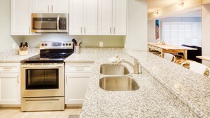 A kitchen with white cabinets, a microwave, stove, and granite countertops. - CRC 1105 - Ground Floor Condo with Great Pool & Beach Access (St Augustine)