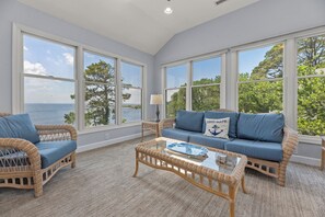 A room with large windows, wicker furniture, and a view of the sea. - La Dolce Vita: Soundfront, Shared Pool, Hot Tub (Corolla)