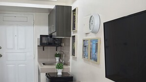 A compact kitchen with a dining area, a flat-screen TV, and a small potted plant. - Oasis in Tagaytay (Tagaytay)