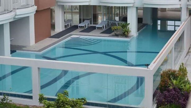 A modern hotel with a central swimming pool, multiple balconies, and lounge chairs. - Oasis in Tagaytay (Tagaytay)