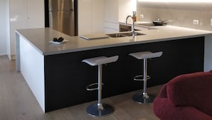 A modern kitchen with a central island, stainless steel appliances, and bar stools.