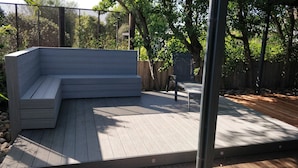 A modern outdoor deck with a built-in bench and a metal table.