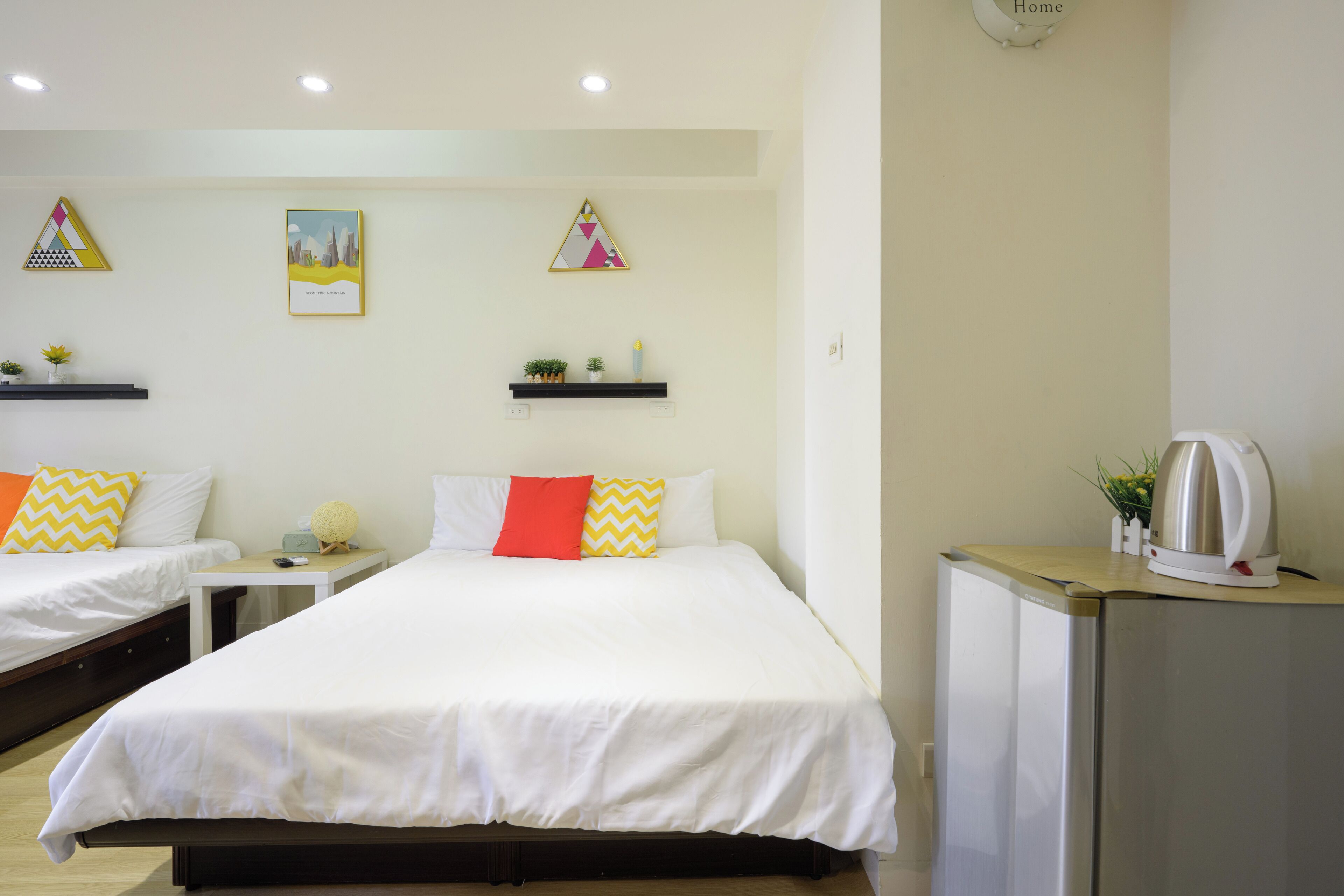 A hotel room with two beds, a small kitchenette, and decorative wall art.