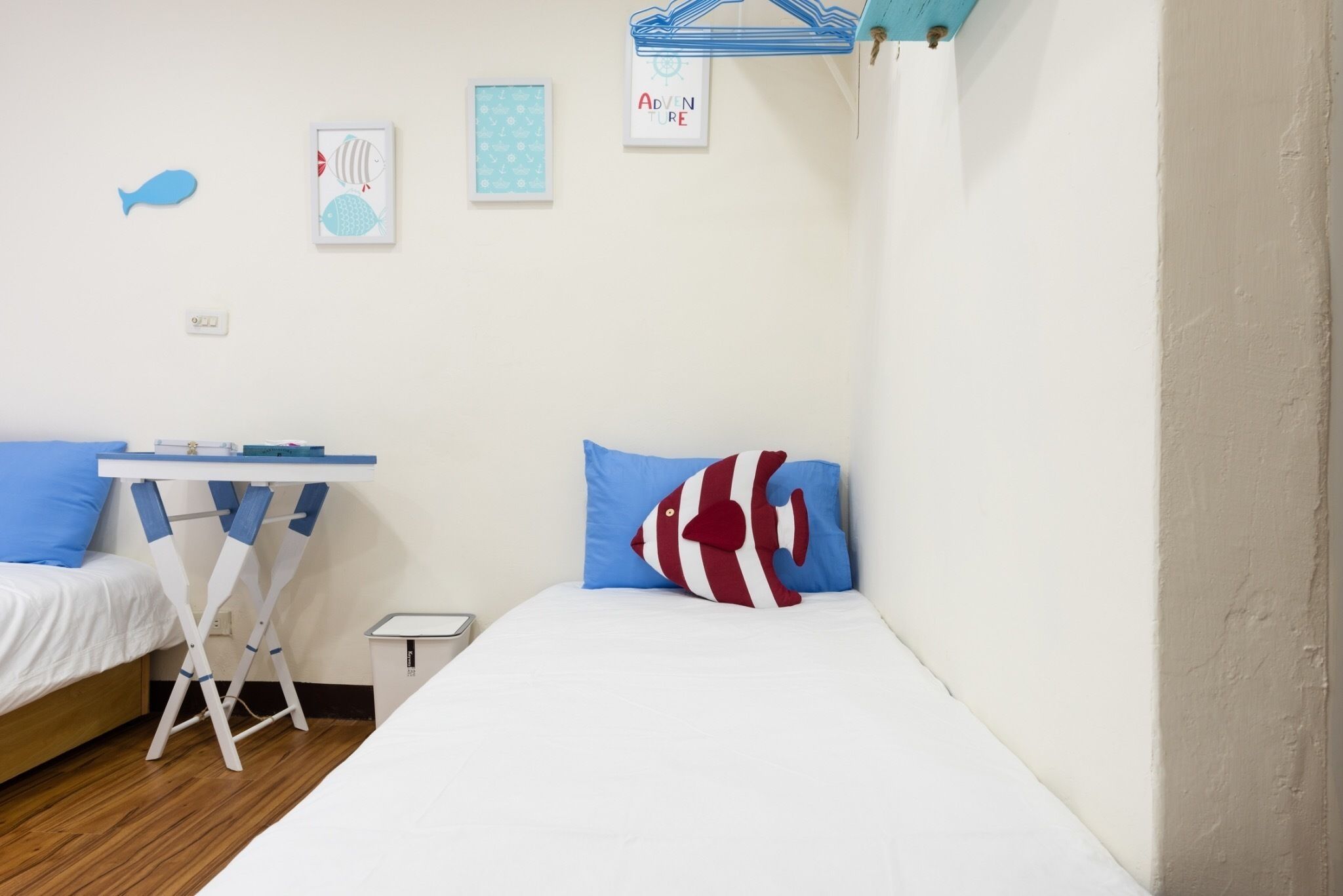 Une chambre avec deux lits, une petite table et une étagère suspendue.