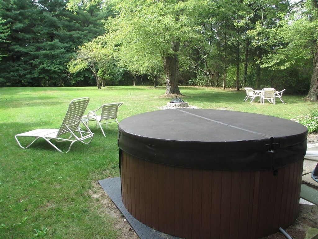 A hot tub in a grassy area with chairs and a table.