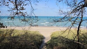 Ein Pfad, der zu einem Strand mit einer hölzernen Konstruktion am Ende führt.