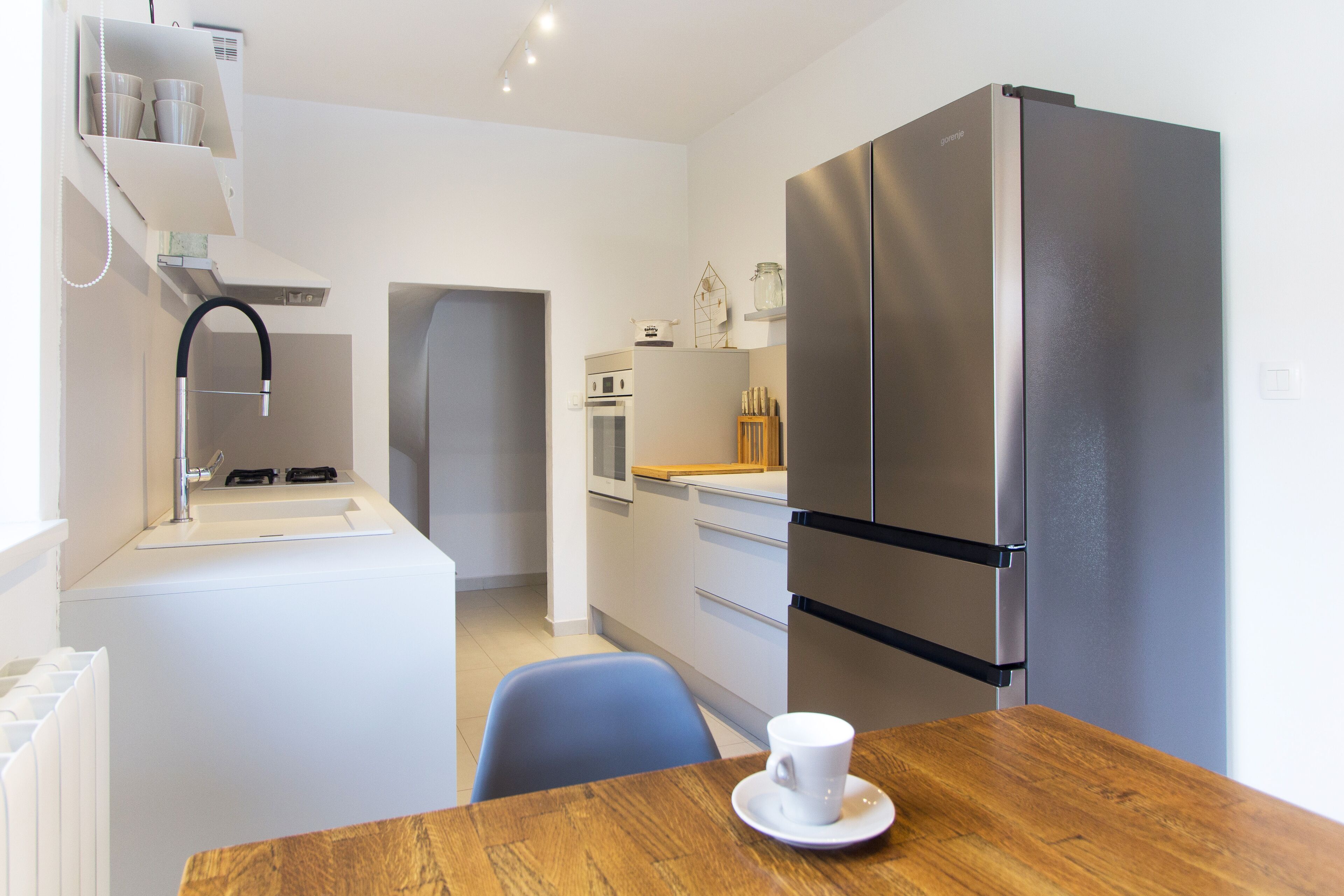 A compact kitchen with a stainless steel refrigerator, a built-in oven, and a sink.