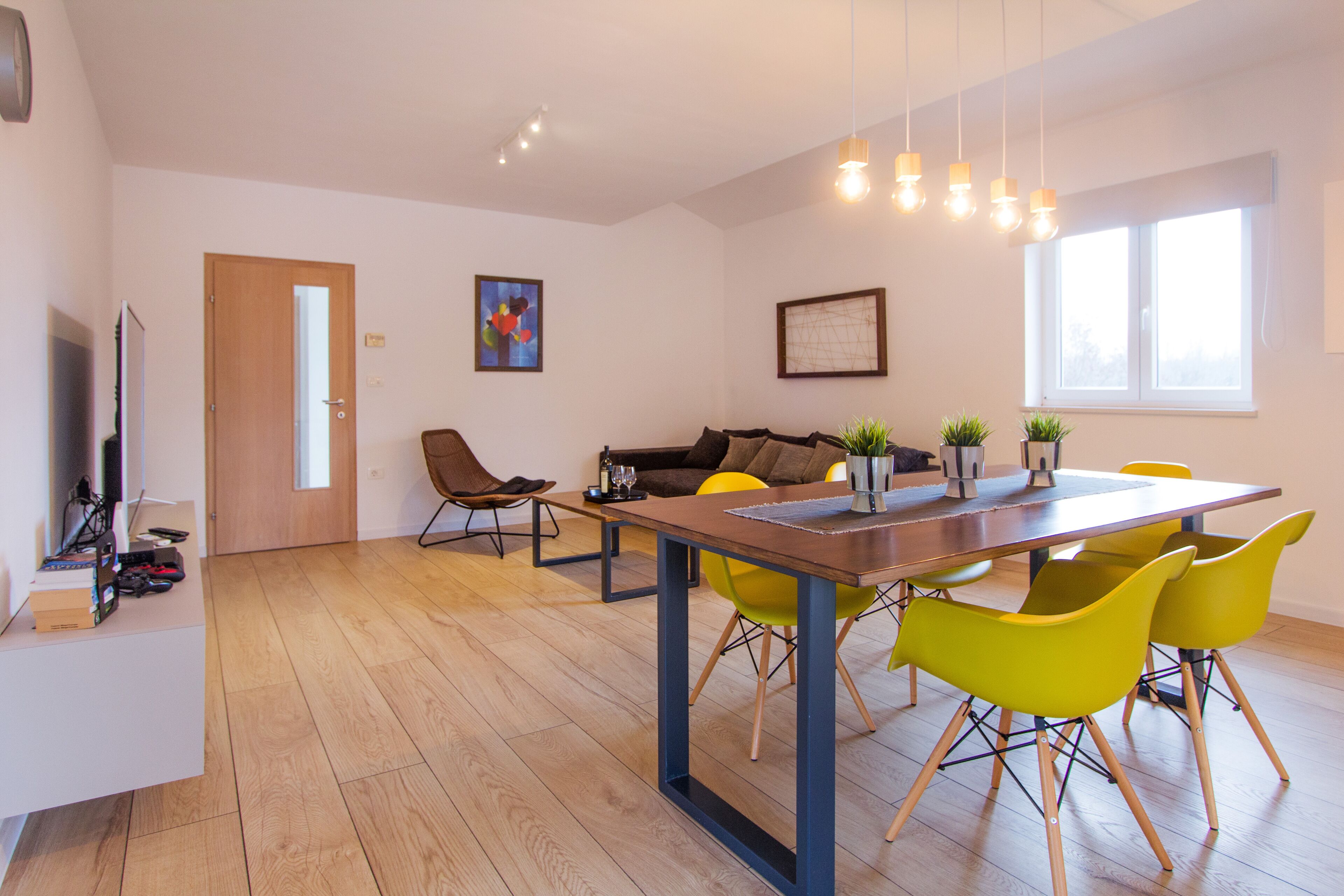 A modern living room with a sofa, a dining table with chairs, and a TV.