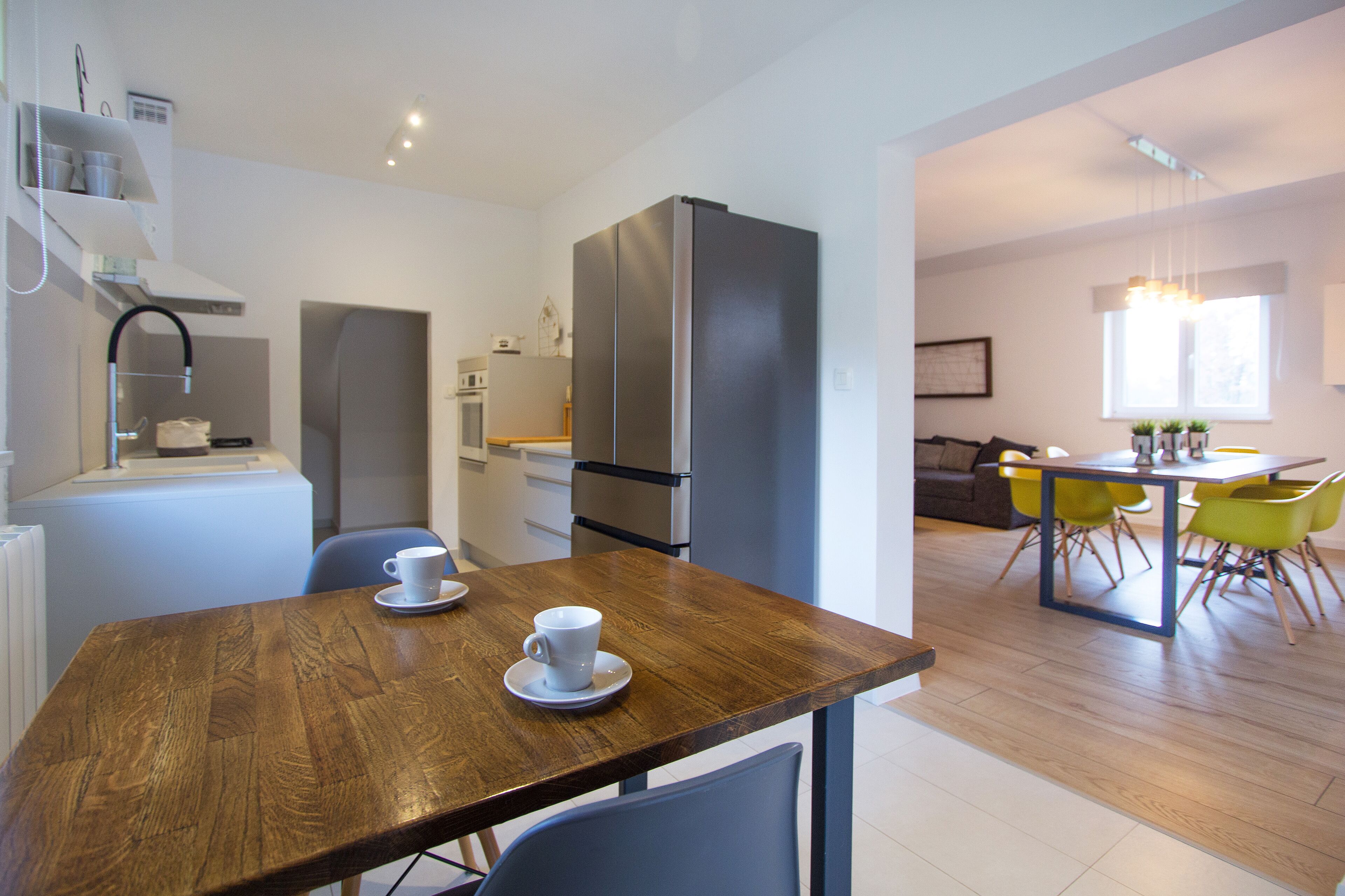 Una cucina moderna con frigorifero, microonde e piano cottura. È presente un'area pranzo con tavolo e sedie in legno.
