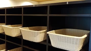 Sechs weiße Korbwannen aus Weidengeflecht stehen auf Regalen in einem Raum mit dunklen Wänden und heller Decke.