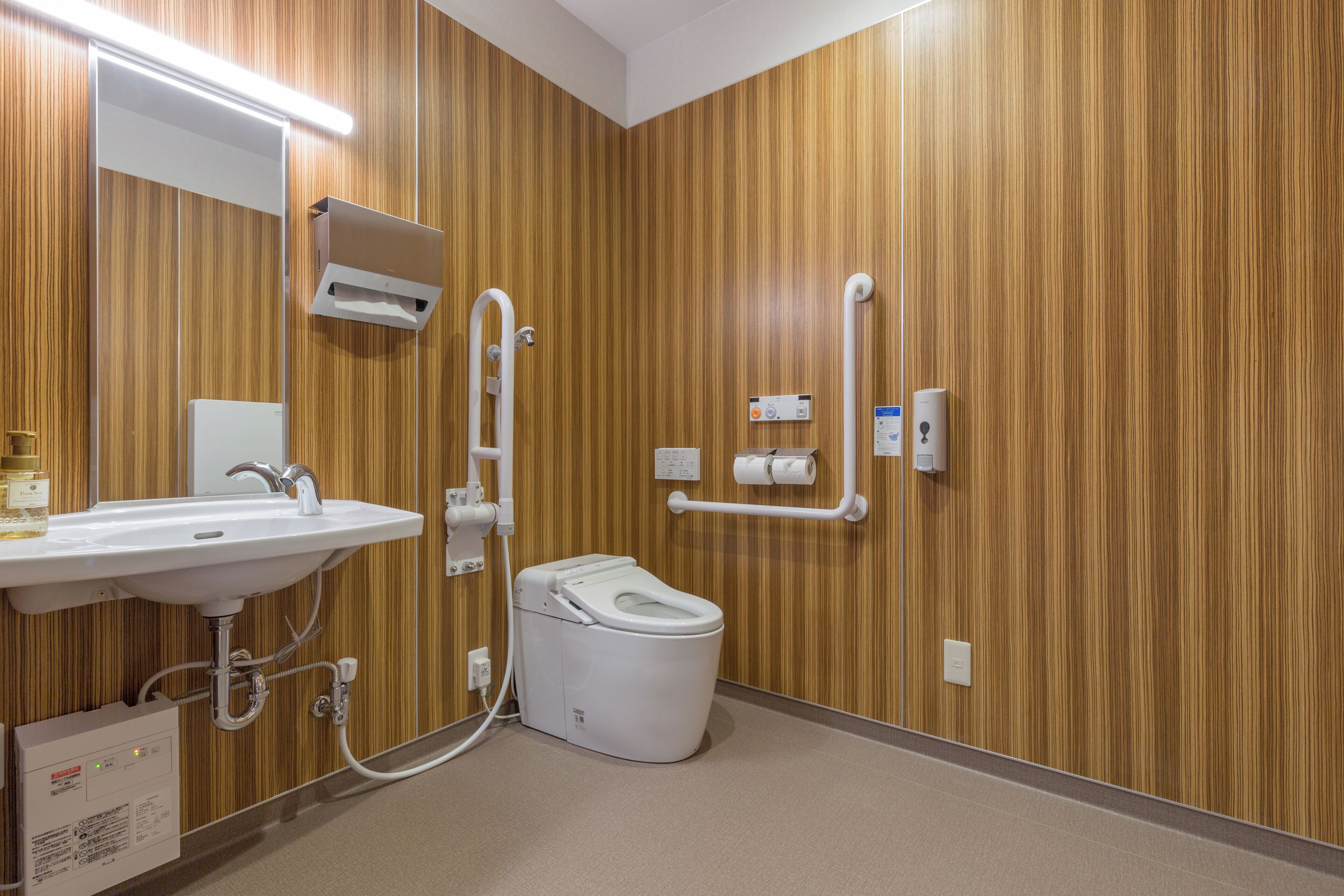 Un baño moderno con pared de madera, un lavamanos blanco, un inodoro y un secador de manos.