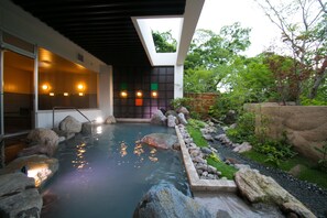 Un spa moderno con aguas termales, rodeado de rocas y vegetación.