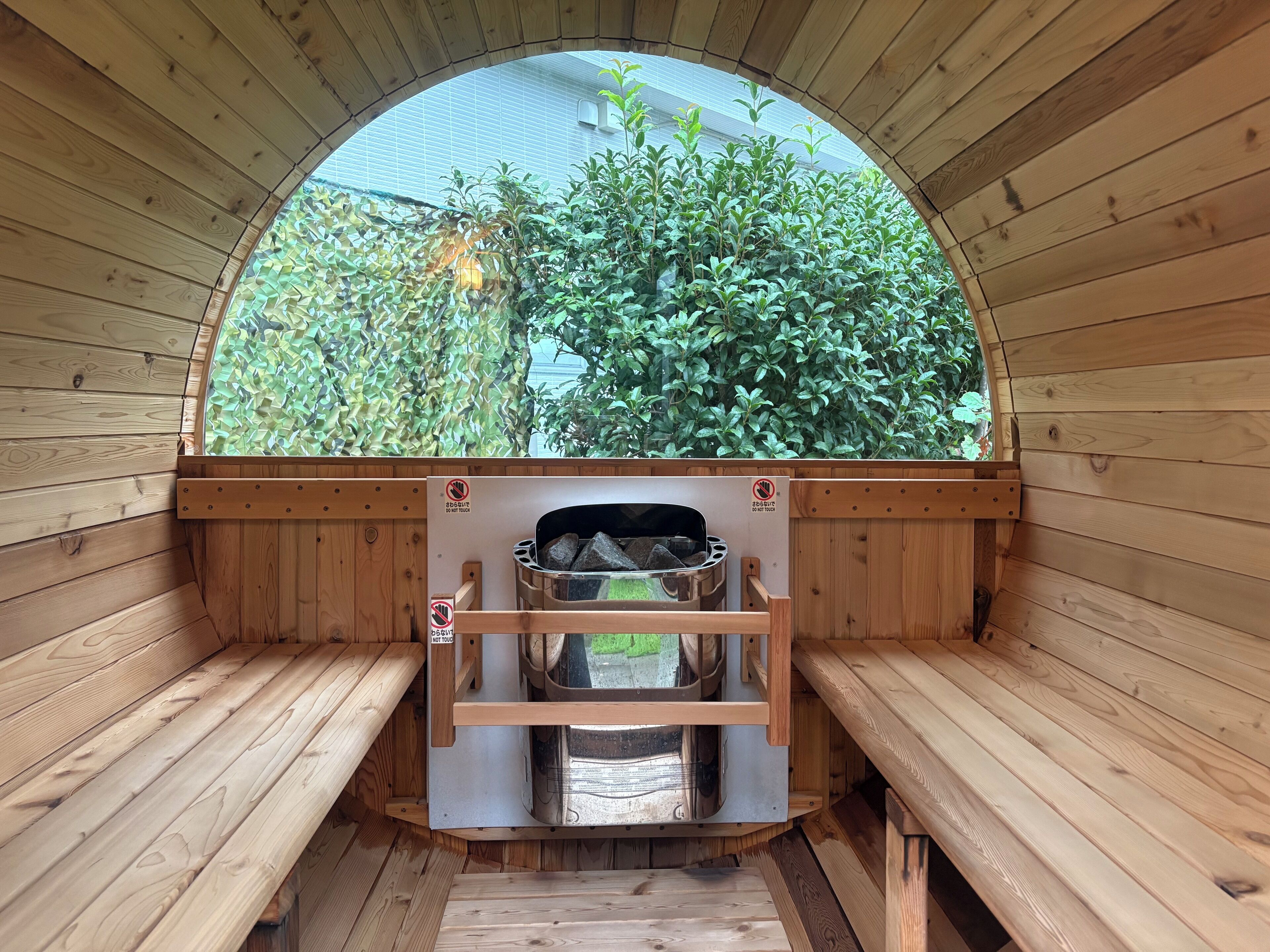Una sauna con paredes de madera, un banco y vistas al exterior con vegetación.