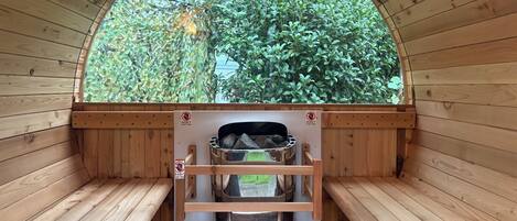 Una sauna con paredes de madera, un banco y vistas al exterior con vegetación.