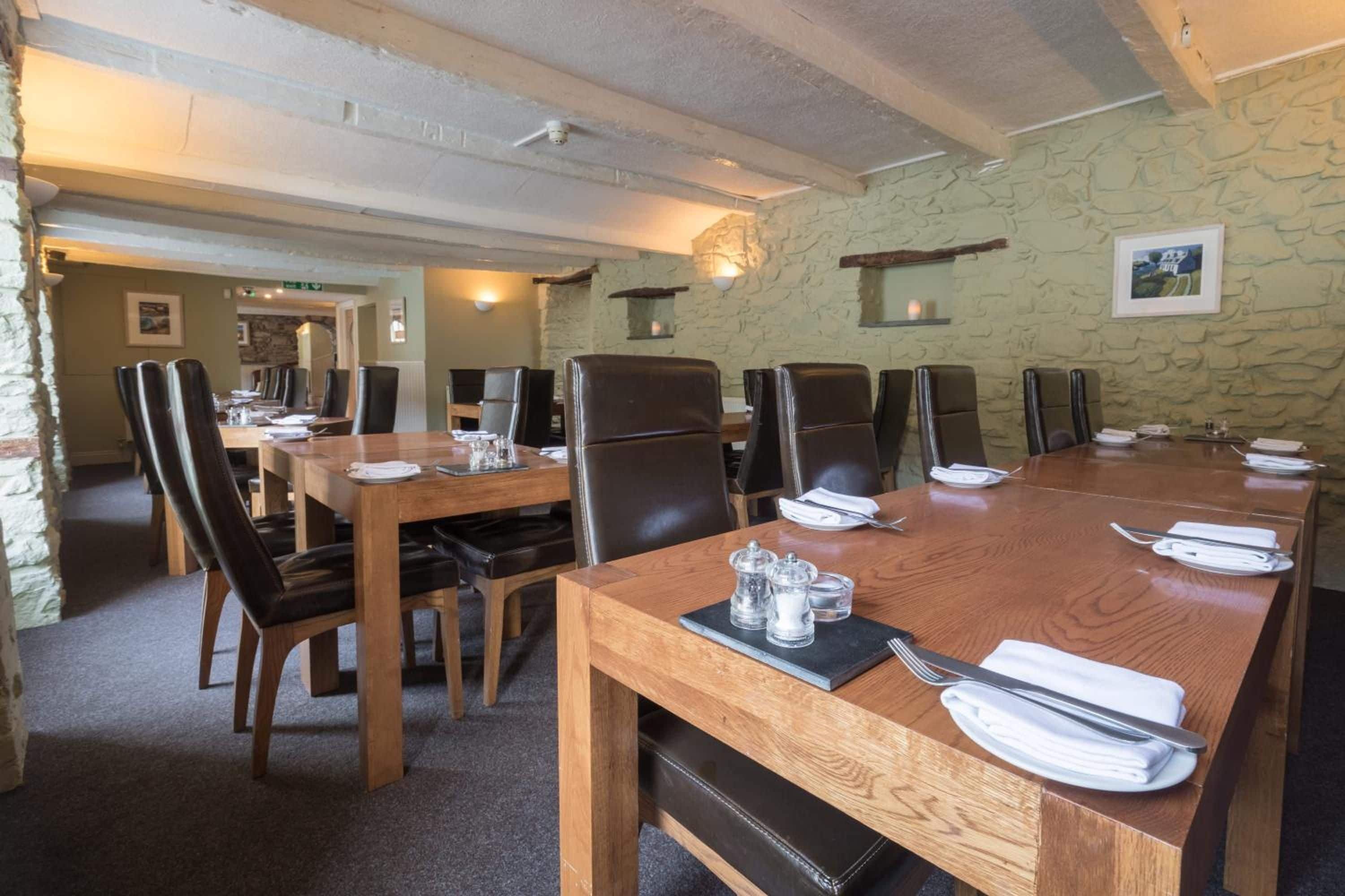 A conference room with a long wooden table, multiple chairs, and a stone wall.