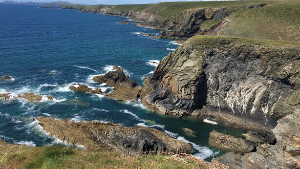 A coastal landscape with rocky cliffs and a clear blue sea.