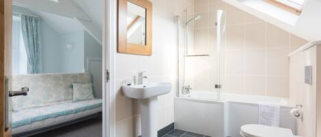 A modern bathroom with a skylight, a bathtub, a toilet, and a sink.