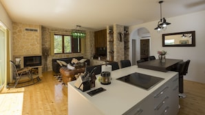 Een moderne keuken met een centraal eiland, stenen muren en een zithoek met een open haard.