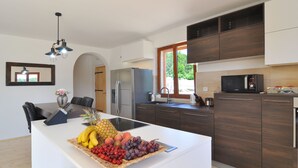 Een moderne keuken met een centraal eiland, donkere houten kastjes, een roestvrijstalen koelkast en een magnetron.