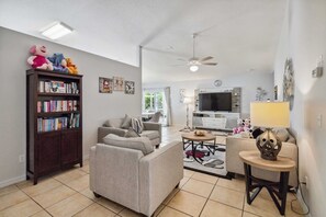 A living room with a sofa, a coffee table, a bookshelf, and a TV.