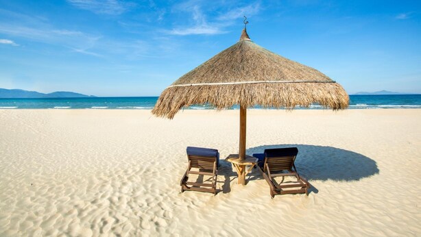 A beach with a thatched umbrella and two wooden lounge chairs. - Summer Beach (Da Nang)