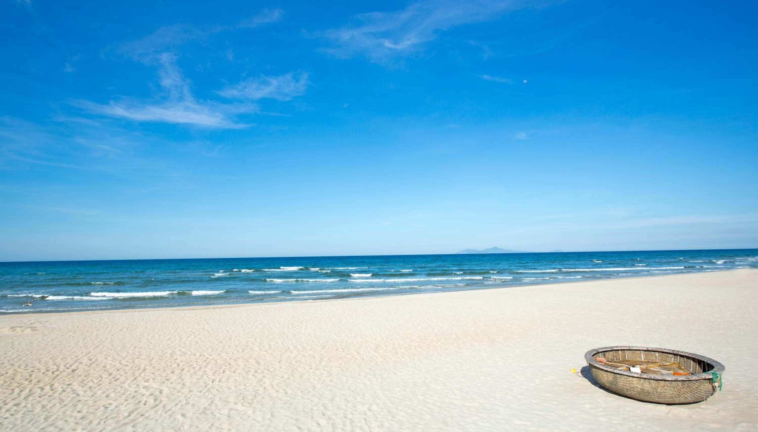 Een strand met een klein bootje in het zand.