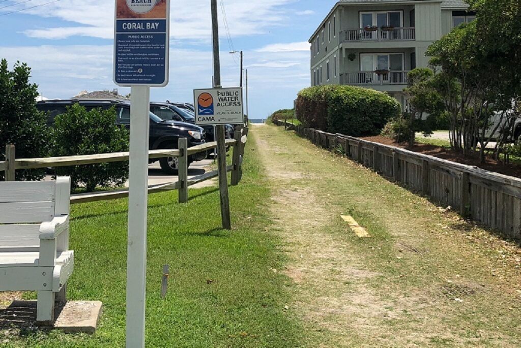 A pathway leading to a beach with a sign indicating public water access.