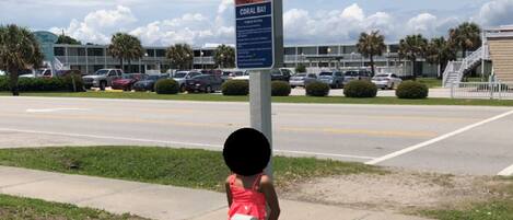 A parking lot with a sign for Atlantic Beach, Coral Bay, and a building in the background.