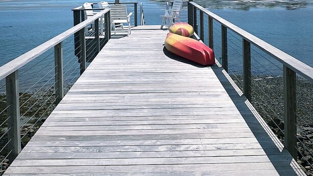 A wooden pier extending into calm waters with a clear sky above.