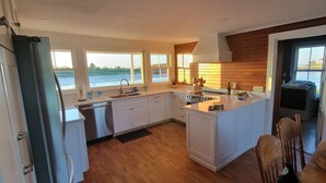 A modern kitchen with white cabinets, a stainless steel dishwasher, and a large island.