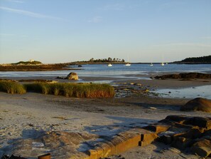A beach with boats, rocky terrain, and grassy areas.