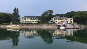 A waterfront property with two yellow houses, a dock, and a small boat.