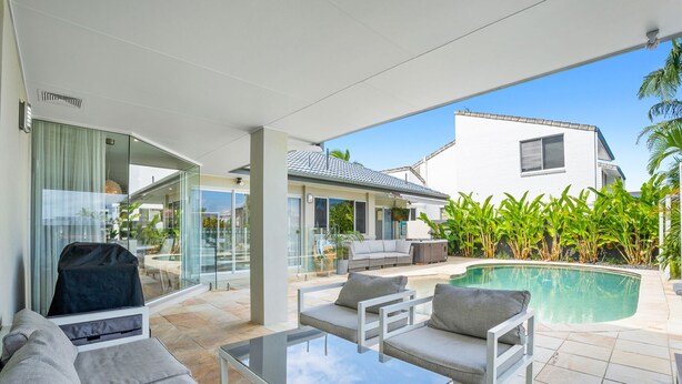 Ein moderner Außenbereich mit einer verglasten Terrasse, einem Pool und einer überdachten Lounge-Ecke.