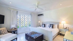 Habitación de hotel con cama, sofá, mesita auxiliar, lámpara y ventana con cortinas.