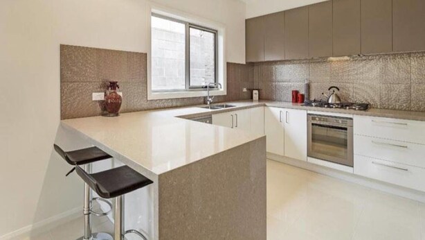 A modern kitchen with a central island, a built-in oven, and a large window. - Signature Townhouse in Doncaster (Doncaster East)
