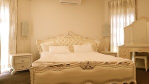 A classic four-poster bed with ornate detailing, a bedside table, a dresser, and a full-length mirror. - Signature Townhouse in Doncaster (Doncaster East)